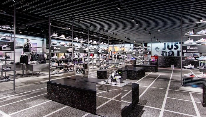 Magasin moderne d'articles de sport présentant une large sélection de chaussures, vêtements et accessoires dans un espace élégant et lumineux.